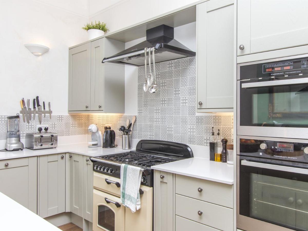 a kitchen with white cabinets and a stove top oven at 3 Berkeley Square Guesthouse in Bristol
