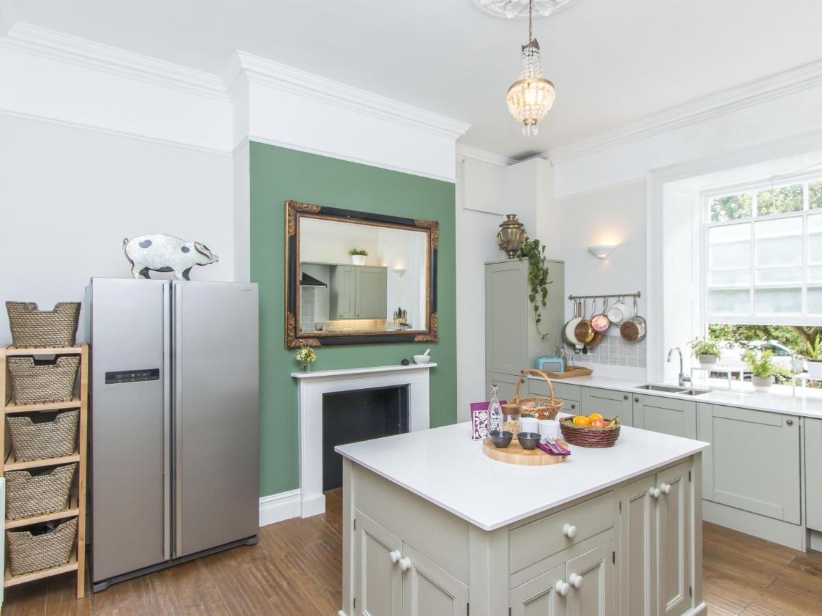 a kitchen with a white refrigerator and a fireplace at 3 Berkeley Square Guesthouse in Bristol