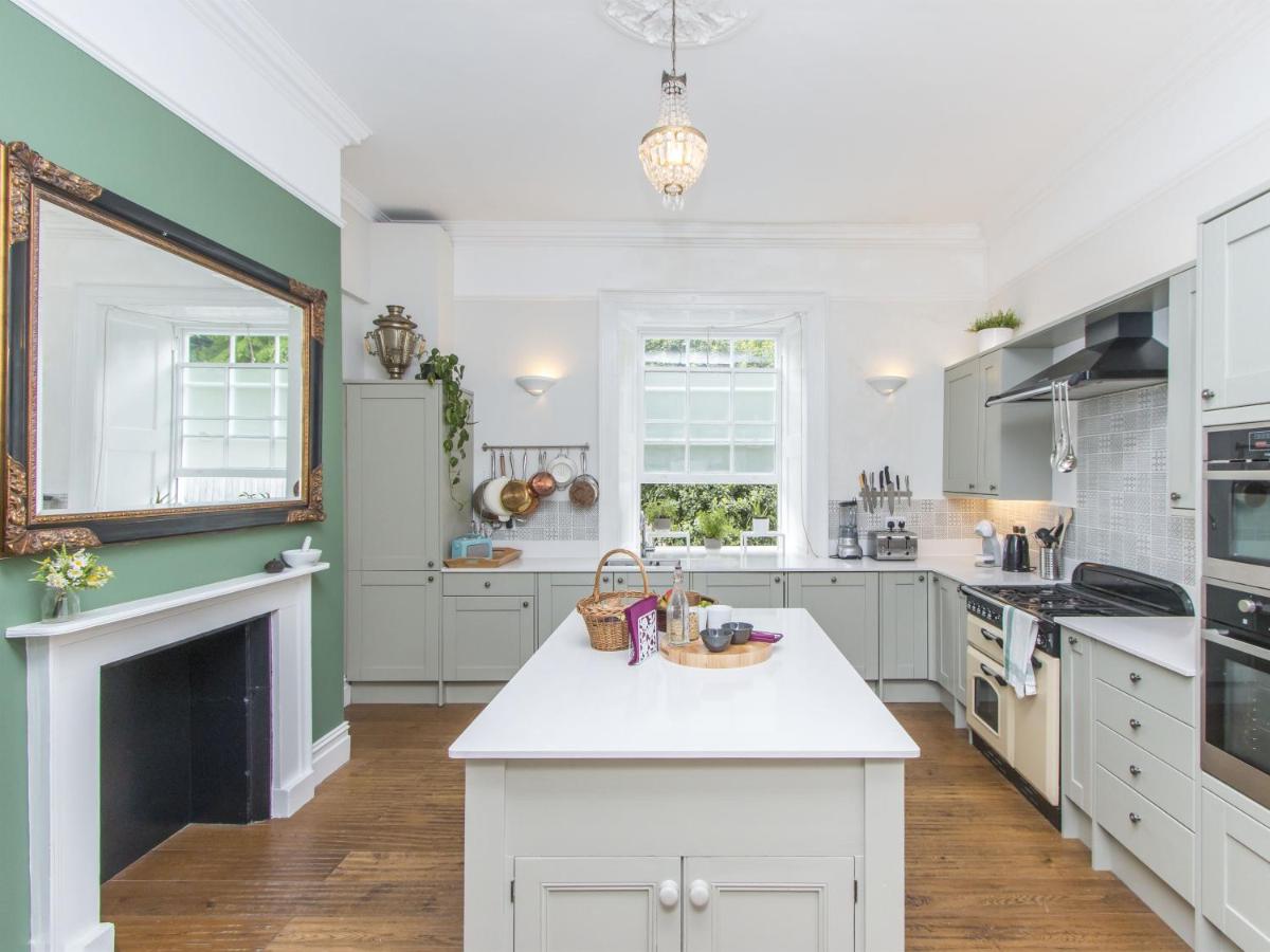 a kitchen with white cabinets and a fireplace at 3 Berkeley Square Guesthouse in Bristol